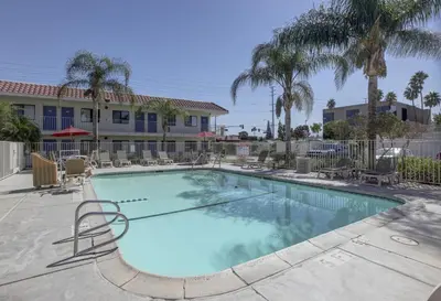 a large swimming pool with chairs and palm trees at Motel 6-Corona, CA in Corona