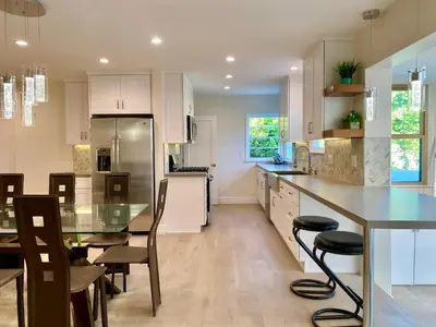 a kitchen with white cabinets and a table and chairs at Oasis with pool and music studio by BENVENU in Los Angeles