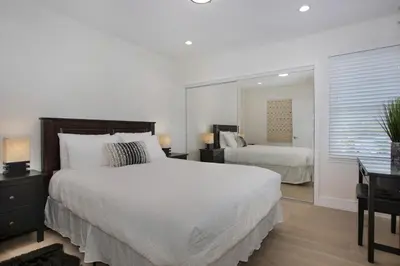 a bedroom with a large white bed and a mirror at Oasis with pool and music studio by BENVENU in Los Angeles