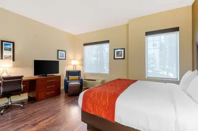 a bedroom with a bed and a desk with a television at Comfort Inn & Suites Near Ontario Airport in Ontario