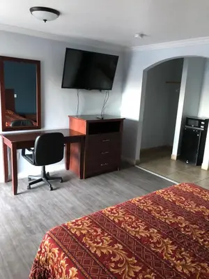 a hotel room with a desk and a television and a bed at La Habra Motel in La Habra