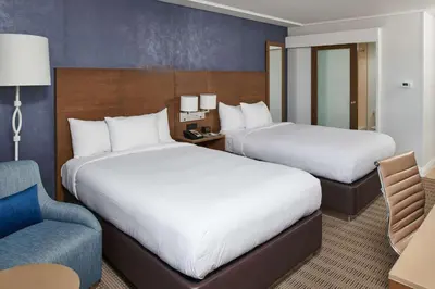 a hotel room with two beds and a chair at DoubleTree by Hilton Torrance - South Bay in Torrance