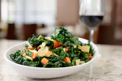 a salad in a white bowl next to a glass of wine at Hilton Woodland Hills/ Los Angeles in Woodland Hills