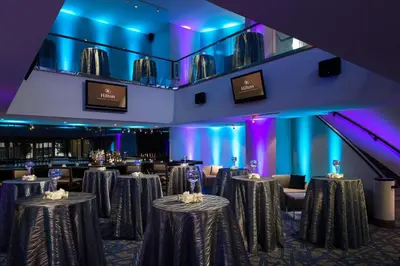 a ballroom with tables and chairs and purple lighting at Hilton Woodland Hills/ Los Angeles in Woodland Hills