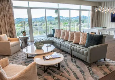 a living room with a couch and tables and windows at The Beverly Hilton in Los Angeles