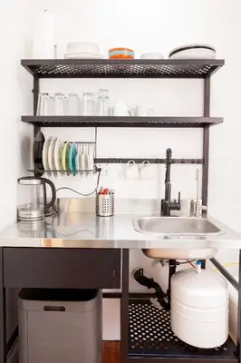 a kitchen counter with a sink and a shelf with dishes at The Steady in Los Angeles