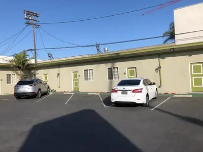 two cars parked in a parking lot in front of a building at Encore Motel Near Marina Del Rey, Culver City & Venice in Los Angeles