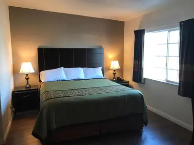 a bedroom with a bed with two lamps and a window at Manhattan Inn & Suites in Manhattan Beach