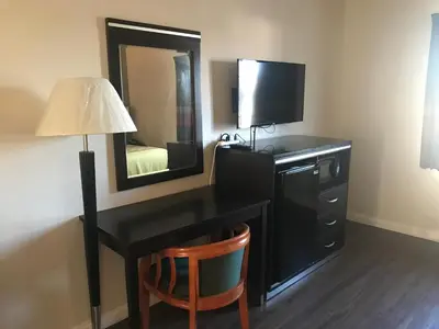 a room with a desk with a television and a mirror at Manhattan Inn & Suites in Manhattan Beach