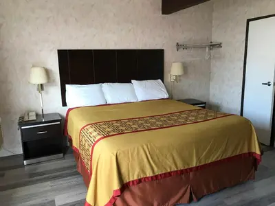 a hotel room with a large bed and two lamps at Manhattan Inn & Suites in Manhattan Beach