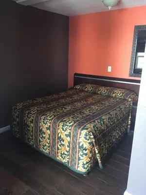 a hotel room with a bed with a blanket on it at Route 66 Motel - Rialto in Rialto