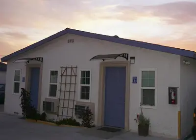 a small white building with a blue door at Route 66 Motel - Rialto in Rialto