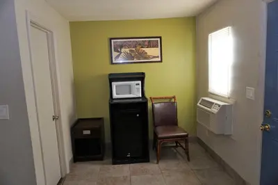 a small room with a microwave and a chair at Route 66 Motel - Rialto in Rialto