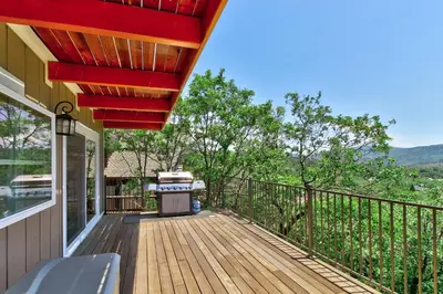 a wooden deck with a grill on a house at Mountain Top Chalet in Lake Arrowhead