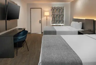 a hotel room with two beds and a desk and a television at Route 66 Motel in Barstow