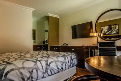 a bedroom with a bed and a table and a television at National 9 Inns in Buttonwillow
