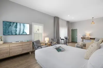 a bedroom with a large white bed and a living room at Sea Sprite Beach Club in Hermosa Beach