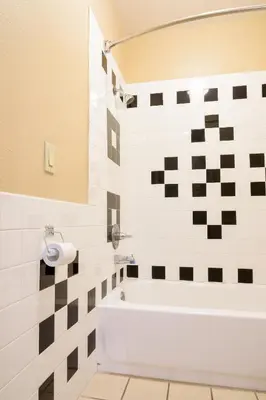 a bathroom with a white tub and black and white tiles at Covina Motel in West Covina