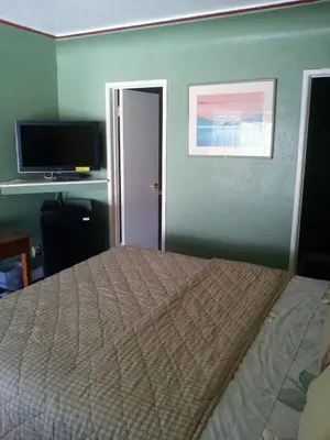 a bedroom with a bed and a flat screen tv at Travel Eagle Inn Motel in Long Beach