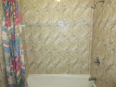 a bathroom with a tub and a tiled wall at Travel Eagle Inn Motel in Long Beach