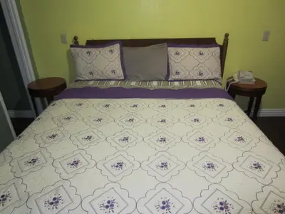 a bed in a bedroom with two tables and a phone at Travel Eagle Inn Motel in Long Beach