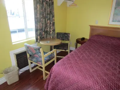 a bedroom with a bed and a table and chairs at Travel Eagle Inn Motel in Long Beach