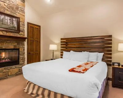 a bedroom with a large bed and a fireplace at Bluegreen Vacations Big Bear Village, an Ascend Collection Resort in Big Bear Lake