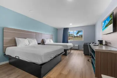 a hotel room with two beds and a desk at Travelodge by Wyndham Fairplex Pomona in Pomona