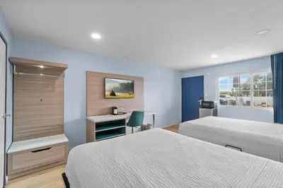 a hotel room with two beds and a desk at Travelodge by Wyndham Fairplex Pomona in Pomona