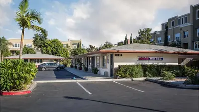 a car parked in a parking lot next to a building at Harbor Motel in Anaheim