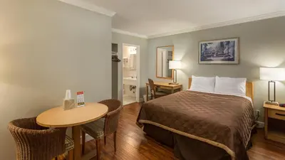 a hotel room with a bed and a table at Harbor Motel in Anaheim