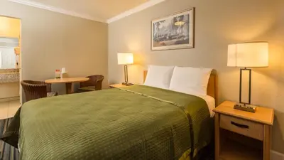 a hotel room with a bed and a table at Harbor Motel in Anaheim