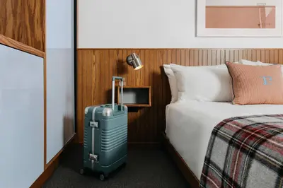 a hotel room with a suitcase next to a bed at Palihotel Culver City in Los Angeles