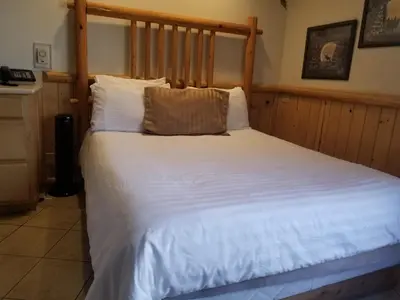 a bedroom with a large white bed with a wooden headboard at Fireside Lodge in Big Bear Lake