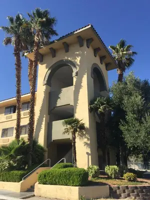 a building with palm trees in front of it at Ramada by Wyndham Barstow in Barstow