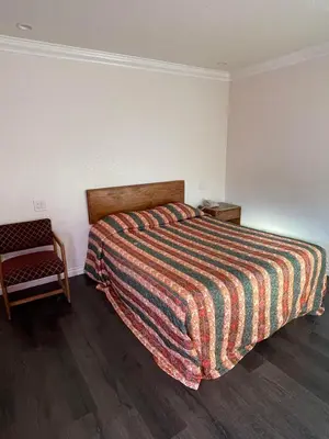 a bedroom with a bed with a colorful blanket and a chair at Welcome Inn & Suites Anaheim in Anaheim
