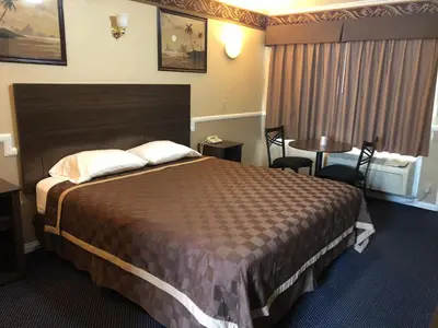 a hotel room with a large bed and a table at Whittier Travel Inn in Whittier