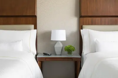 two beds with white pillows and a table with a lamp at The Westin Long Beach in Long Beach
