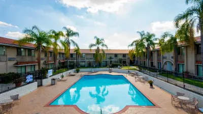 a large swimming pool in a courtyard with palm trees at Motel 6 - Anaheim Hills, CA in Anaheim