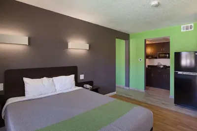 a bedroom with a bed and a kitchen with green walls at Studio 6-Barstow, CA in Barstow