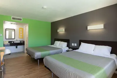 two beds in a hotel room with green walls at Studio 6-Barstow, CA in Barstow