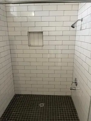 a bathroom with a white tiled shower with a window at Rocky Inn Motel in Lynwood