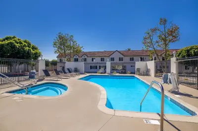a swimming pool with chairs and a house at SureStay Plus Hotel by Best Western Upland - Ontario North in Upland
