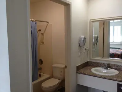 a bathroom with a sink and a toilet and a mirror at Scottish Inns in Long Beach