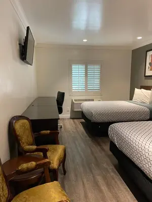a room with two beds and a desk and a chair at La Casa Inn in Pasadena
