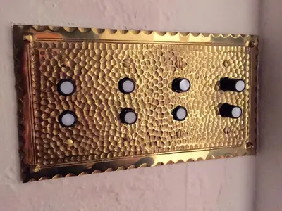 a gold switch with black dots on a wall at SpanishFairytale4bd3ba in San Pedro