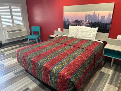 a hotel room with a bed and a chair at Sahara Inn - Los Angeles in Los Angeles