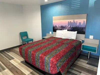 a hotel room with a bed and a chair at Sahara Inn - Los Angeles in Los Angeles