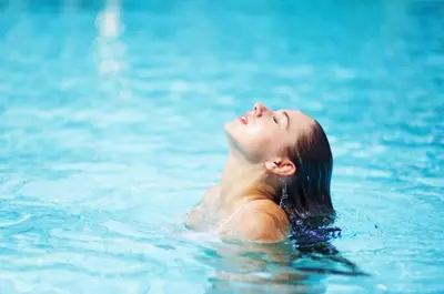 a woman laying in the water in a swimming pool at Designer Penthouse 2 Bedroom with Balcony Beverly Hills Adjacent in Los Angeles