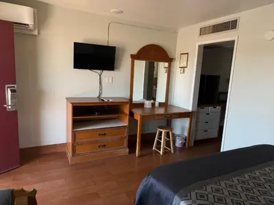a bedroom with a dresser and a desk with a television at Apple Valley Motel in Apple Valley